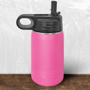 The Kodiak Coolers Wisconsin Luxemburg Casco Spartans 12 oz pink water bottle features a black flip top straw lid and carrying handle, with a laser engraved design, shown on a wooden surface with a white and gray background.
