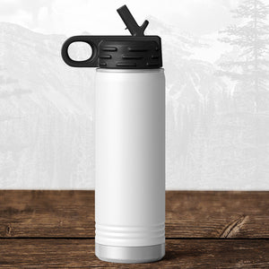 A Kodiak Coolers Wisconsin Green Bay Bulldogs 20 oz water bottle with a flip top straw lid features a laser-engraved design and stands on a wooden surface against a blurred mountain background.