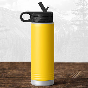A Kodiak Coolers Wisconsin Luxemburg Casco Spartans 20 oz water bottle with flip top straw and carrying handle sits on a wooden surface, featuring a laser engraved design, set against a scenic mountain background.