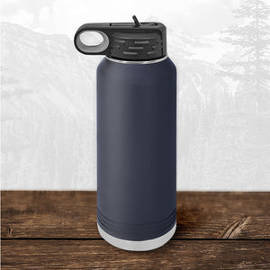 A 32 oz Wisconsin Green Bay Bulldogs water bottle by Kodiak Coolers with a laser-engraved design and flip top straw rests on wood, displaying school pride.