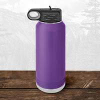 A 32 oz Kodiak Coolers water bottle featuring a laser-engraved Wisconsin Green Bay Bulldogs design and a flip top straw sits on a wooden surface with mountains in the background—ideal for Bulldogs fans.