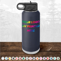 A Custom Tumbler from Kodiak Coolers featuring a handle cap and UV-printed text "YOUR LOGO UV PRINTED HERE" in a rainbow gradient, set against a backdrop of pine trees in a forest. This black water bottle makes an ideal corporate promotional gift and is available for a limited time with a $250 minimal order.