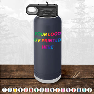 A Custom Tumbler from Kodiak Coolers featuring a handle cap and UV-printed text "YOUR LOGO UV PRINTED HERE" in a rainbow gradient, set against a backdrop of pine trees in a forest. This black water bottle makes an ideal corporate promotional gift and is available for a limited time with a $250 minimal order.