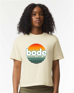 A person wearing the designerapp BODE Summer Camp 2026 "OG Logo" Women's Crop Top (Comfort Colors 3023CL), a boxy fit light tee featuring a sunset graphic and "bode SUMMER CAMP '26" on the front.
