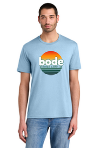 A man wearing a Printify 2026 Bode Summer Bootcamp OG Logo Unisex Tri Blend T-Shirt in light blue, featuring a sunset graphic and "bode SUMMER CAMP '23" on the front.