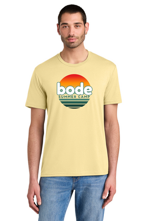 A man wears the Printify 2026 Bode Summer Bootcamp OG Logo Unisex T-Shirt DM130 Tri Blend, a light yellow, lightweight tee featuring a sunset graphic and "bode summer camp" logo.