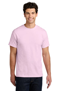 A man stands smiling in a plain white setting, wearing a light pink Gildan 5000 Heavy 100% Cotton Custom T-Shirt (Pack of 36) with screen printed logo, and dark jeans.