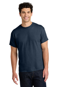 A man with dark curly hair smiles while wearing a Gildan 5000 Heavy 100% Cotton Custom T-Shirt (pack of 36, custom screen printed logo included), paired with dark jeans against a white background.