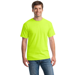 A man in blue jeans wears a bright neon yellow Gildan 5000 Heavy 100% Cotton Custom T-Shirt (Pack of 36) with custom screen printed logo, standing and smiling against a plain white background.