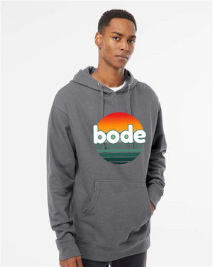 A person wears the printify 2026 Bode Summer Bootcamp — OG Logo Hoodie Sweatshirt, an Independent Trading Co. SS4500 unisex gray cotton-poly fleece hoodie with a colorful front logo, standing against a plain white background.