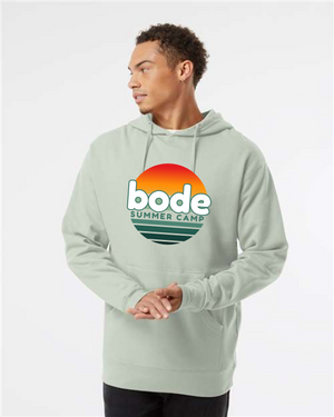 Someone wears the Printify 2026 Bode Summer Bootcamp — OG Logo Unisex Hoodie Sweatshirt (Independent Trading Co. SS4500) in light green, featuring a sunset graphic and adjustable hood, standing against a plain backdrop.