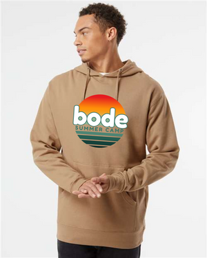 A person wears the Printify 2026 Bode Summer Bootcamp — Cali Sunset Hoodie Sweatshirt (SS4500), featuring a cotton-poly fleece and sunset logo, looking to the side against a plain background.