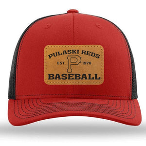 The Pulaski Reds Baseball Est. 1978 Richardson 112 Snapback Trucker Cap by designerapp features a red and black design with a tan leather patch reading "Pulaski Reds Baseball Est. 1978" and a large "P" in the center.