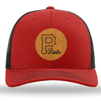 The Pulaski Reds Baseball Richardson 112 Snapback Trucker Cap by designerapp features a custom brown circular leather patch with a bold black "P" and "Reds" in script, all on a red and black trucker hat.