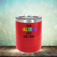 A red Custom UV Printed Drinkware - ONE TIME SPECIAL OFFER from Kodiak Coolers with a customizable space for a full-color logo, placed on a wooden surface with a blurred, sparkly background. Perfect for coffee mugs or travel tumblers, it also offers an engraving option for personalized flair.