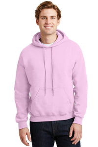 A man wears a light pink Gildan Heavy Blend™ Hooded Sweatshirt 18500 (Pack of 36) with custom screen printed logo, made sustainably, and dark jeans as he stands facing forward and smiles at the camera.