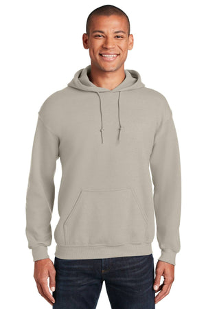 A person stands smiling in a (Pack of 36) Gildan Heavy Blend™ Hooded Sweatshirt 18500 with custom screen printed logo, paired with dark jeans, against a plain white background.