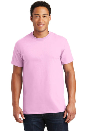 A person stands against a white background, wearing a Gildan - 100% US Cotton T-Shirt 2000 in plain pink, paired with dark jeans.