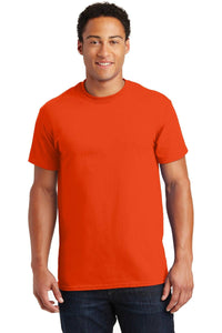 Wearing a vibrant orange Gildan - 100% US Cotton T-Shirt 2000 and dark jeans, a person stands against a white background, facing the camera.