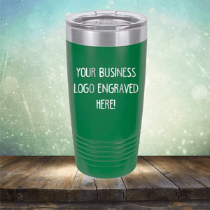 Green stainless steel Kodiak Coolers Custom Logo 20 oz Tumblers - SPECIAL OFFER - Front side Logo Included with the words "YOUR BUSINESS LOGO ENGRAVED HERE!" against a blurred, light-filled background. The tumbler, perfect for personalized drinkware or as a promotional gift, is placed on a wooden surface.
