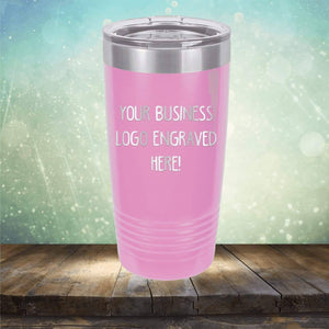 A pink insulated tumbler with a metallic lid sits on a wooden surface, perfect for personalized drinkware. The tumbler displays "Your Business Logo Engraved Here!" and features a blurred decorative background, making it an ideal promotional gift. This Custom Logo 20 oz Tumblers - SPECIAL OFFER - Front side Logo Included from Kodiak Coolers is perfect for any occasion.