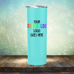 A light blue tumbler with a silver lid stands on a wooden surface. The text on the tumbler reads "Your full color logo goes here" in black and multi-colored lettering. The background is a sparkling gradient, making this Kodiak Coolers Custom UV Printed Drinkware - ONE TIME SPECIAL OFFER one of the most eye-catching tumblers available for custom engraving.