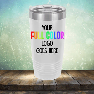 A silver and white tumbler sits on a wooden surface with a green and blue bokeh background. The Custom UV Printed Drinkware - ONE TIME SPECIAL OFFER by Kodiak Coolers has text reading "YOUR FULL COLOR LOGO GOES HERE.