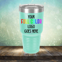 A mint green tumbler with a metal rim on a rustic wooden surface. The text on the tumbler reads, "Your Full Color Logo Goes Here" in various colors. Perfect for engraving, this stylish piece is ideal for coffee mugs or tumblers alike. This is the Kodiak Coolers Custom UV Printed Drinkware - ONE TIME SPECIAL OFFER.