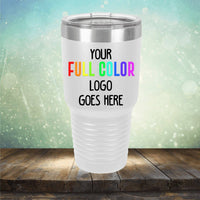 A white travel tumbler with the text "Your Full Color Logo Goes Here" printed on it, placed on a wooden surface against a blurred, light-colored bokeh background. These Custom UV Printed Drinkware - Single Side Printing Included in Price from Kodiak Coolers make for perfect personalized coffee mugs or engraved wine cups for any occasion.