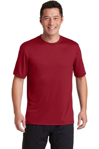 A person is smiling while wearing a Hanes Cool Dri Performance T-Shirt 4820 in red, along with black pants, against a neutral background.