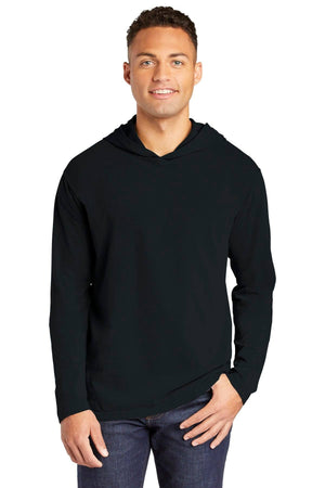A man wearing a Comfort Colors Ring Spun Long Sleeve Hoodie Shirt 4900 in black and blue jeans stands facing the camera with a neutral expression.