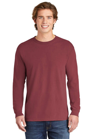 A young man, smiling at the camera, stands facing forward wearing blue jeans and a Comfort Colors Heavyweight Ring Spun Long Sleeve T-Shirt 6014 in maroon.