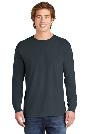 A young man smiles at the camera, wearing a Comfort Colors Heavyweight Ring Spun Long Sleeve T-Shirt 6014 in dark gray and blue jeans, standing against a white background.