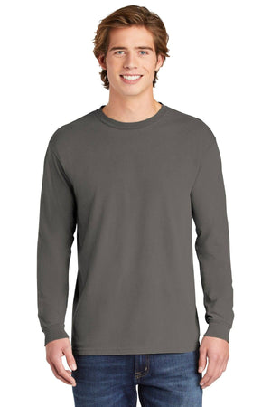 A young man with light brown hair stands and smiles at the camera against a white background, wearing a gray Comfort Colors Heavyweight Ring Spun Long Sleeve T-Shirt 6014 and blue jeans.