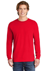 A young man smiles at the camera, wearing a Comfort Colors Heavyweight Ring Spun Long Sleeve T-Shirt 6014 in plain red, paired with blue jeans.