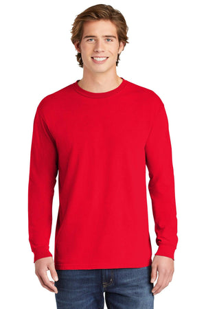 A young man smiles at the camera, wearing a Comfort Colors Heavyweight Ring Spun Long Sleeve T-Shirt 6014 in plain red, paired with blue jeans.