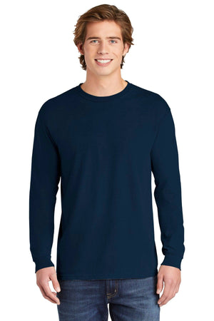 A young man smiles at the camera in blue jeans and a Comfort Colors Heavyweight Ring Spun Long Sleeve T-Shirt 6014 by Comfort Colors, standing against a white background.