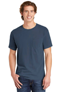 A young man with light brown hair smiles against a plain background, wearing the Comfort Colors Heavyweight Ring Spun Pocket T-Shirt 6030 in blue, paired with blue jeans.