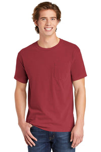A young man with light brown hair smiles in a Comfort Colors Heavyweight Ring Spun Pocket T-Shirt 6030 in red and blue jeans, standing against a white background.