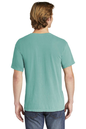 A person with light brown hair, wearing a teal Comfort Colors Heavyweight Ring Spun Pocket T-Shirt 6030 and blue jeans, stands with their back to the camera.