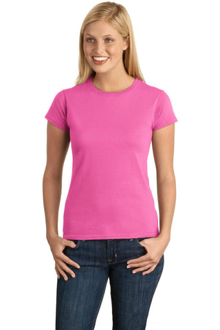 A person is wearing a Gildan Softstyle Ladies T-Shirt 64000L in pink, made from ring spun cotton, paired with jeans, standing with hands on hips and smiling.