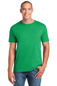 A person in a Gildan Softstyle T-Shirt 64000 in green, featuring a modern classic fit, paired with blue jeans smiles with one hand casually in their pocket.