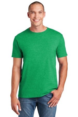 A person in a Gildan Softstyle T-Shirt 64000 in green, featuring a modern classic fit, paired with blue jeans smiles with one hand casually in their pocket.
