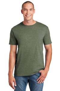 A person wearing the Gildan Softstyle T-Shirt 64000 in green, made from soft ring-spun cotton, pairs it with jeans and smiles at the camera, showcasing a modern classic fit.