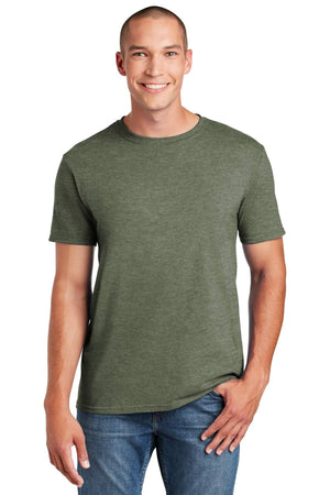 A person wearing the Gildan Softstyle T-Shirt 64000 in green, made from soft ring-spun cotton, pairs it with jeans and smiles at the camera, showcasing a modern classic fit.