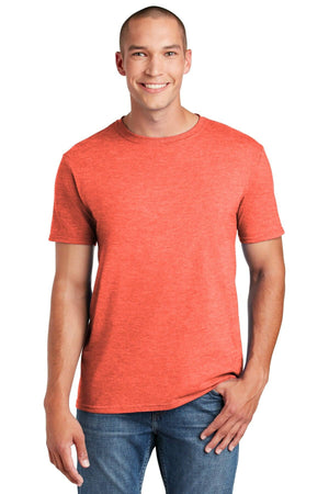 A person in a Gildan Softstyle T-Shirt 64000, an orange ring-spun cotton by Gildan, and blue jeans stands smiling against a white background in a modern classic fit.