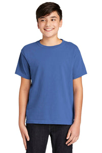 A smiling boy faces forward in black pants and a Comfort Colors Youth Ring Spun T-Shirt 9018, made from 100% ring spun cotton, against a white background.