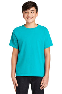A smiling boy wears a Comfort Colors Youth Ring Spun T-Shirt 9018, made of soft ring spun cotton in bright teal, paired with dark pants against a plain white background.