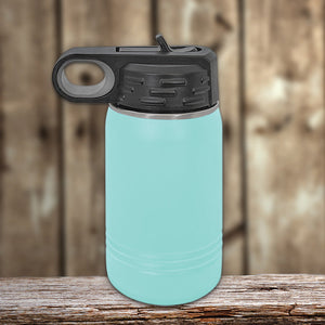 A personalized Kodiak Coolers turquoise water bottle with a black flip-top lid, featuring vacuum-sealed insulation technology, on a wooden surface against a wooden backdrop.