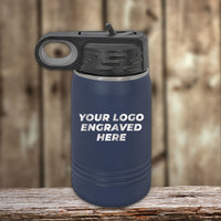 A 12 oz blue Custom Kids Water Bottle by Kodiak Coolers, personalized with your logo, design, or names in front, features a black lid and sits on a wooden surface—now available with special Black Friday sale volume pricing for a limited time.